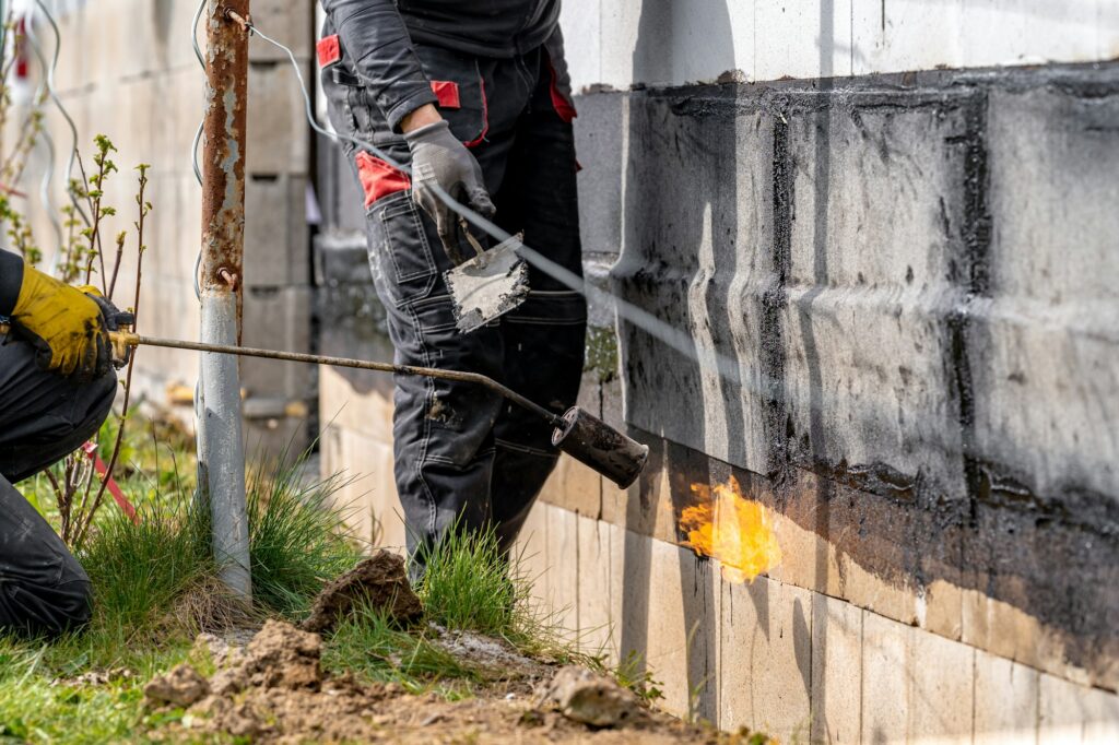 installation of protective waterproofing on the foundation and walls of the building. warmed by an