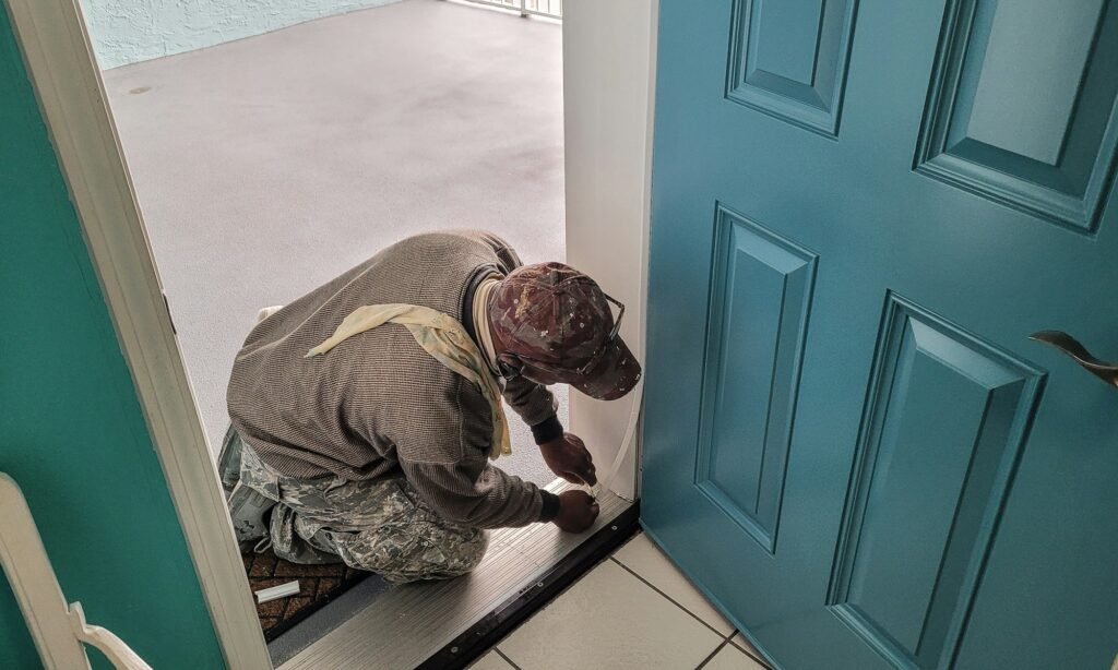 Worker opens door to home sweet home to weather strip for winter in condo remodel.